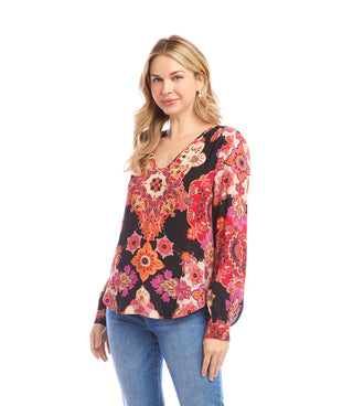 Woman wearing a colorful floral patterned blouse on a white background. Karen Kane V-Neck Long Sleeve Shirred Blouse, Red/Magenta Print
