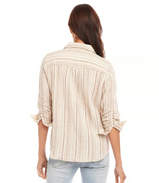 A woman wearing a beige and white metallic striped ruched sleeve shirt with a collar, paired with blue jeans.