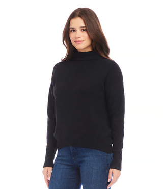 A woman wearing a black mock neck sweater with long sleeves, paired with blue jeans.