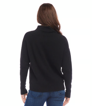 A woman wearing a black mock neck sweater with long sleeves, paired with blue jeans.