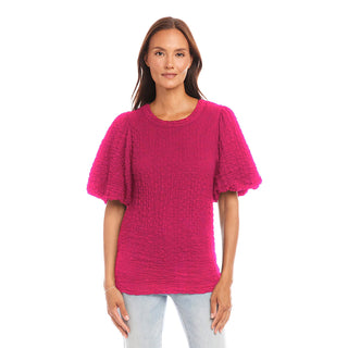 Woman wearing a Karen Kane bright pink textured top on a white background