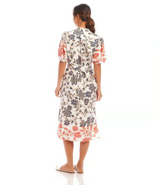 A woman wearing a floral shirtdress with puff sleeves, collar, and a removable fabric belt.