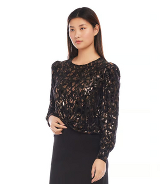 A woman wearing a black and copper, puff sleeve top with a cheetah print and metallic foil detail.