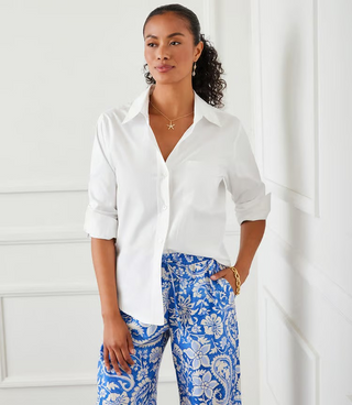 A woman wearing a white Karen Kane button-up shirt with rolled sleeves and a collar, paired with blue pants