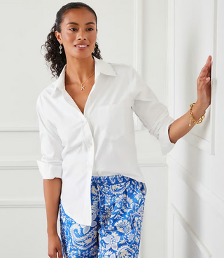 A woman wearing a white Karen Kane button-up shirt with rolled sleeves and a collar, paired with blue pants