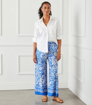 A woman wearing a white Karen Kane button-up shirt with rolled sleeves and a collar, paired with blue pants