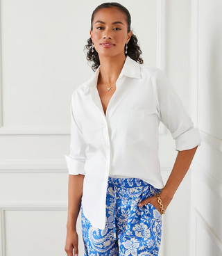 A woman wearing a white Karen Kane button-up shirt with rolled sleeves and a collar, paired with blue pants