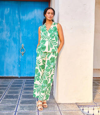 Woman wearing a green leaf-patterned dress standing in front of a blue door.