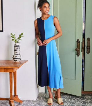 A sleeveless midi dress with color blocking in navy and blue, worn by a model standing against a white background.