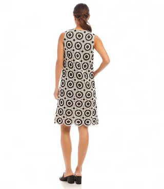 A model wearing a sleeveless knee-length crochet shift dress with a V-neck and scalloped hem, in black and white.