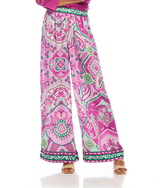 A pair of high-waisted, wide-leg pants with a paisley print in pink and green hues on a crepe fabric. They feature a pull-on elastic waistband