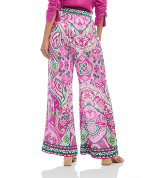 A pair of high-waisted, wide-leg pants with a paisley print in pink and green hues on a crepe fabric. They feature a pull-on elastic waistband