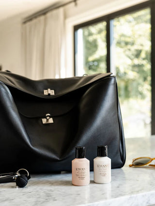 Black handbag on a marble surface with mini lavant mini hand care set