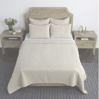 A king-sized quilt set with matching euro shams displayed on a bed, with a natural beige color binding and diamond pattern quilting.