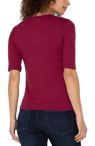 Person wearing a red shirt and dark jeans on a white background