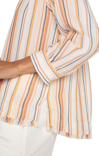 A woman wearing a multicolor striped Liverpool woven top with 3/4 sleeves and a V-neckline, paired with white shorts.