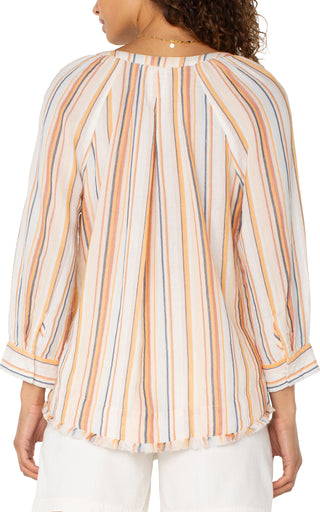 A woman wearing a multicolor striped Liverpool woven top with 3/4 sleeves and a V-neckline, paired with white shorts.