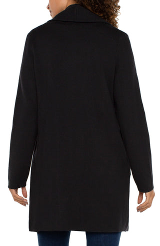 A woman wearing a Liverpool black long sleeve open front shawl sweater coatigan over a white top, paired with blue jeans.