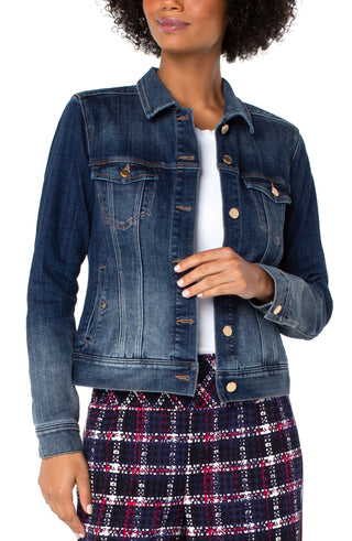A woman wearing a blue denim jacket with ombre wash and golden hardware, featuring a front closure and two front pockets, paired with a red and black plaid skirt.
