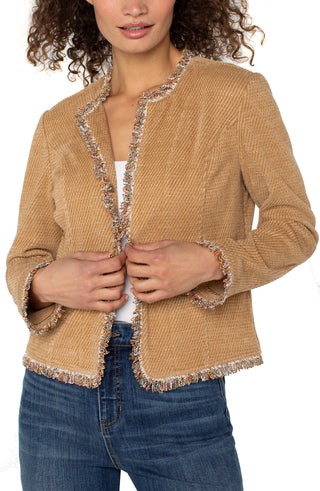 Woman wearing a beige textured jacket with decorative trim on a white background