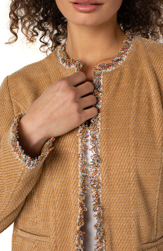 Close-up of a person wearing a brown cardigan with decorative trim.
