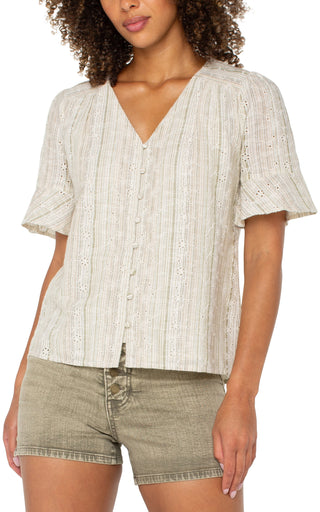 A woman wearing a green and tan striped elbow peplum sleeve crossover woven top with short sleeves, paired with beige shorts.