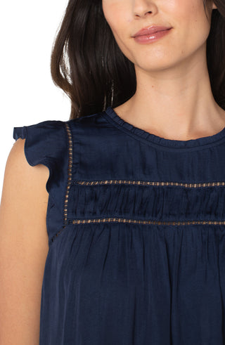 Navy blue top with ruffled sleeves and decorative stitching on a white background