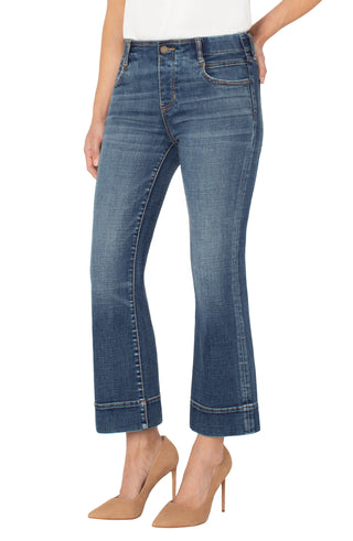 Blue jeans with hem detail worn by a person on a white background