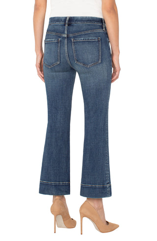 Blue jeans with hem detail worn by a person on a white background