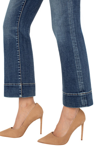 Blue jeans with hem detail worn by a person on a white background