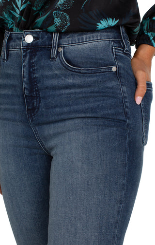 A pair of hi-rise crop flare jeans with a cut hem in a juniper valley shade, featuring a front view on a female model.