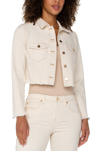 A woman wearing a beige Liverpool jacket with fray hem, paired with a white top and white jeans.