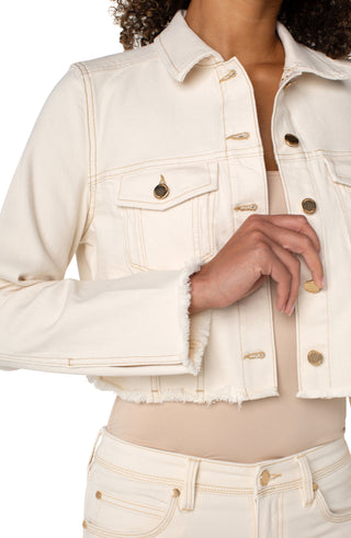 A woman wearing a beige Liverpool jacket with fray hem, paired with a white top and white jeans.