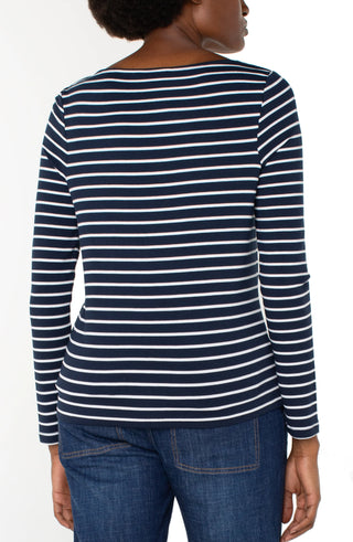 A woman wearing a dark navy long sleeve boatneck knit top with white stripes, paired with jeans.