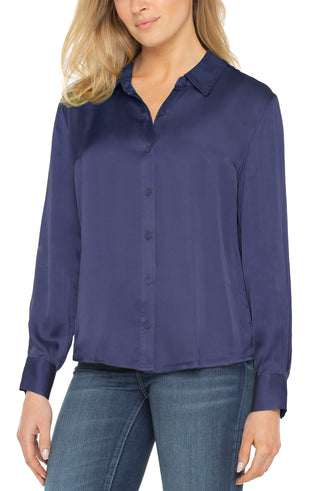 Woman wearing a navy blue blouse and jeans on a white background