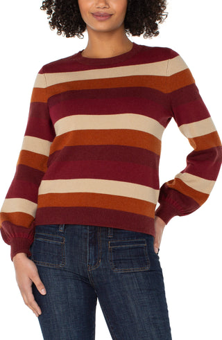 Person wearing a striped sweater with red, orange, and beige colors.
