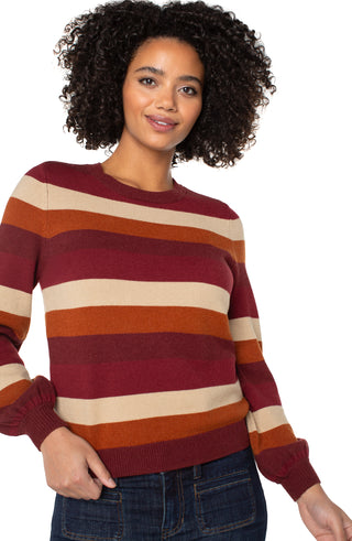 Woman wearing a striped sweater with red, orange, and beige colors on a white background