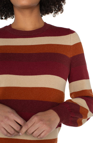 Close-up of a person wearing a striped sweater with red, orange, and beige colors.