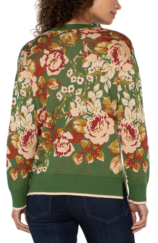 Floral patterned sweater on a model with a green background