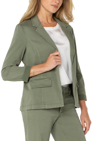 A model in a fitted olive green blazer with rolled sleeves and front pockets.