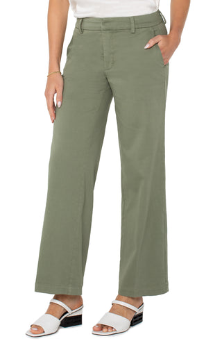 A pair of olive green wide leg Kelsey trousers with a structured waistband, paired with a white top and white sandals.