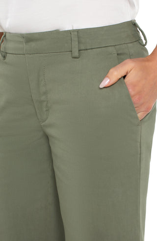 A pair of olive green wide leg Kelsey trousers with a structured waistband, paired with a white top and white sandals.