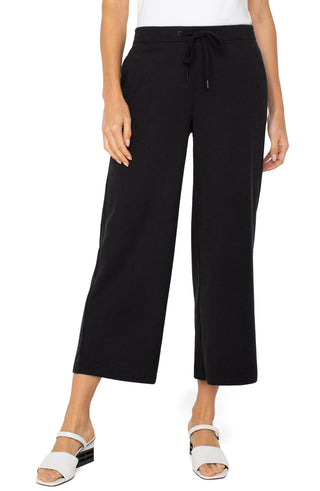 A model wearing black wide leg crop trousers with a drawstring waist.