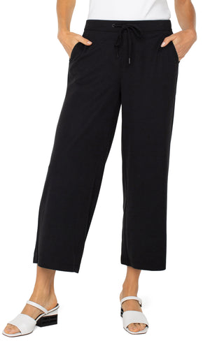 A model wearing black wide leg crop trousers with a drawstring waist.