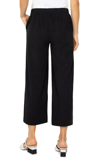 A model wearing black wide leg crop trousers with a drawstring waist.