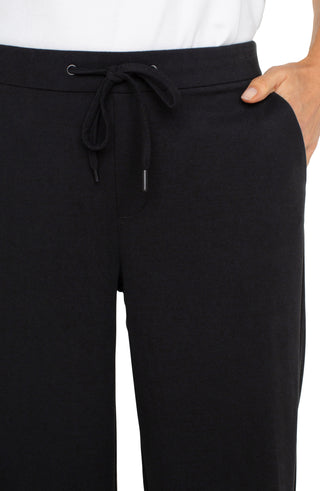 A model wearing black wide leg crop trousers with a drawstring waist.