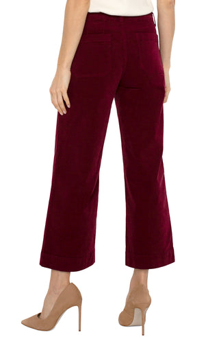 A pair of ruby red corduroy crop wide-leg pants with patch pockets, featuring a mid-rise waist and a flared leg design.