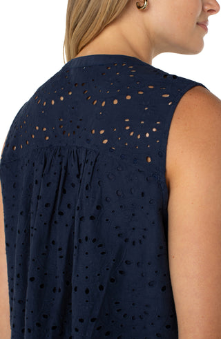 A navy, sleeveless woven top with pintuck details and a scalloped edge finish, worn by a model paired with jeans.