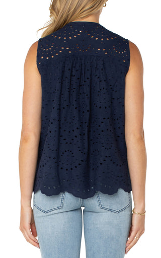 A navy, sleeveless woven top with pintuck details and a scalloped edge finish, worn by a model paired with jeans.