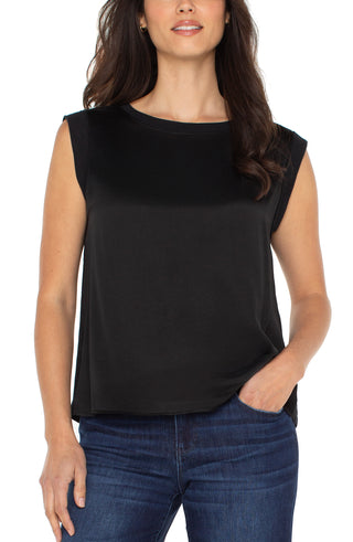 Woman wearing a black sleeveless top and blue jeans on a white background